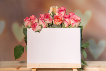 Pink roses on a wooden background, white place for text, easel, pink background for the holiday of February 14 or March 8