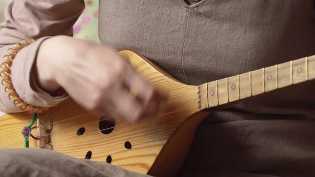 Person strumming and playing a Panduri, traditional string instrument from Georgia - Eye level close up