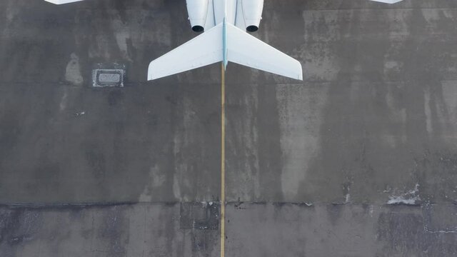 Behind large private airplane parked on concrete airport, reveal shot