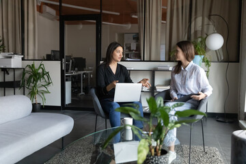 Diverse colleagues working together, discussing project, young Indian businesswoman holding laptop,...