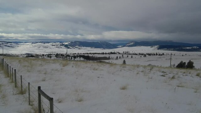 lawn covered with white snow in a winter wonderland landscape in the Nicola Valley Canada on a cloudy day. Reversed drony dolly shot