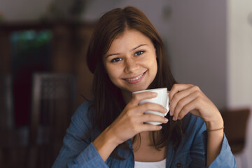 Young girl in cafe with cup of hot chocolade with wide smile