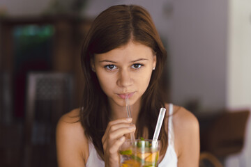 Young girl in cafe drinking cold lemonade
