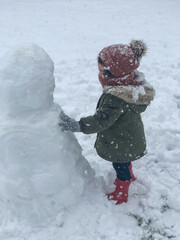 child playing in snow. Little girl making a snowman.