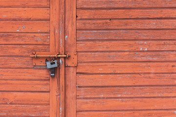 Wooden garage door. Metal padlock background. Peeling paint wood. Vintage rustic gate. Empty copy space grunge door texture.