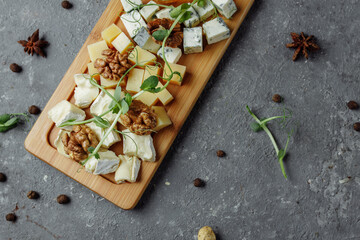 Close-up of a cheese plate. 4 types of cheese, soft white brie cheese, camembert, semi-soft briques, blue, roquefort, hard cheese