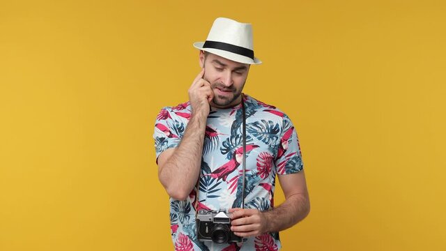 Puzzled excited traveler tourist man in summer clothes hat isolated on yellow background studio. Passenger traveling on weekend. Air flight journey concept. Holding index finger up with great new idea