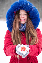 Young smiling woman in red hold gift box outdoors