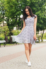 Young elegant girl posing at city street. Pretty beautiful business woman in elegant dress against city background.