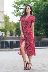 Young elegant girl posing at city street. Pretty beautiful business woman in elegant dress against...