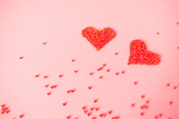 Composition of the heart as a symbol of love laid out from red beads on pink background for valentine's day.