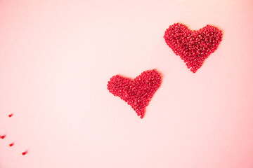 Composition of the heart as a symbol of love laid out from red beads on pink background for valentine's day.