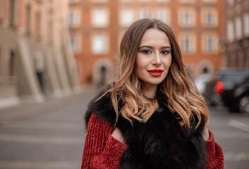 Naklejka na ściany i meble Outdoor photo of fashionable female model walking around city in winter vacation. Fashionable girl walking on Warsaw street in Old Town. Poland.