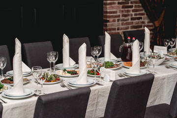 table with white tablecloth and napkins, set of cutlery with snacks for the banquet. Catering, server tables for bonquet