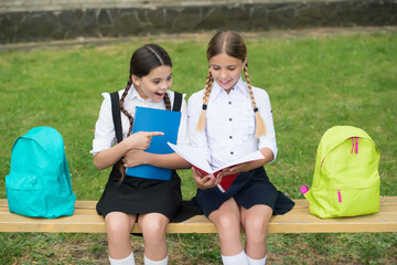 The more you read, the more you learn. Little children read book sitting on bench. School...
