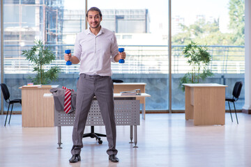 Young male employee doing sport exercises in the office