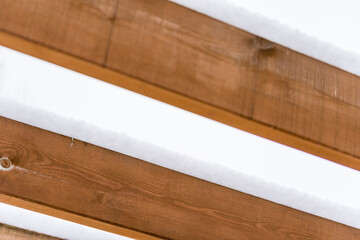 Wooden beam covered with snow. Wood construction outside after snowfall.