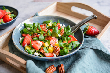 Healthy lettuce salad with mango, strawberry, pecan nuts and Feta cheese