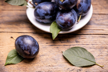 heap of a purple damsons plums over grunge wooden background. natural fruits. healthy eating concept