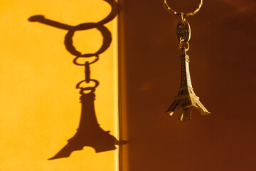 Metal keychain in the form of the Eiffel Tower and the shadow on the wall, a souvenir from Paris with love, a trip to France. High quality photo