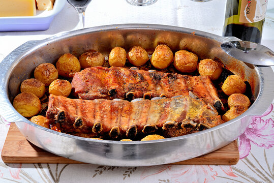 Costela de Proco com Batatas assadas no forno servidos na mesa numa forma de alum&iacute;nio