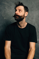 Portrait of a courageous guy with a beard and mustache on a canvas background