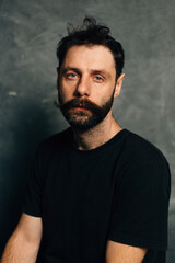 Obraz premium Portrait of a courageous guy with a beard and mustache on a canvas background