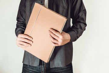 Shoot of man with blue shirt who is standing, holding folder on a white background.