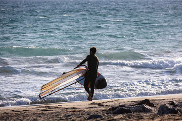 Man with windsurf board on seascape background with sea and clouds