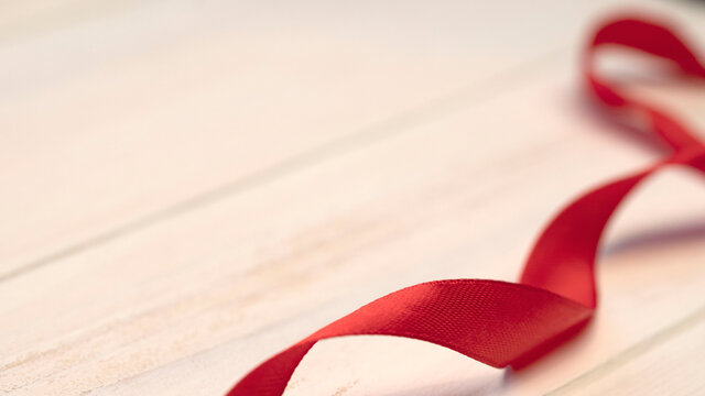 red ribbon on wood background for valentines day with copy space, curly swirls or red silk, elegant, satin ribbon decoration for romantic message, expressing love and attention celebration