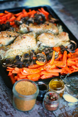 Fototapeta na wymiar Selective focus. Baking tray with baked chicken parts, carrots and mushrooms. Korean chicken with vegetables.