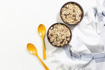 Full grain muesli with dried fruits in two clay bowl on white kitchen table. Healthy and tasty breakfast idea. Copy space for your text.