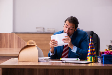 Young male employee celebrating Christmas at workplace