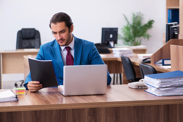 Fototapeta premium Young male employee working at workplace