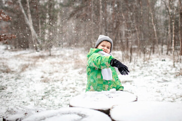 Fototapeta na wymiar Kids enjoy first snow together in winter forest and play snowballs, active winter weekend, seasonal outdoor activities, happy family lifestyle