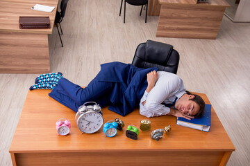Fototapeta na wymiar Young male employee sleeping in the office in time management co