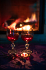 two glasses with red wine, near the fireplace, evening, vertical