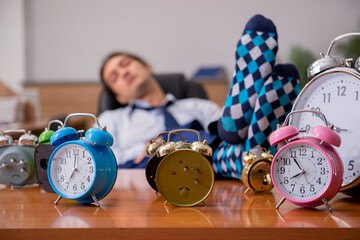 Young male employee sleeping in the office in time management co