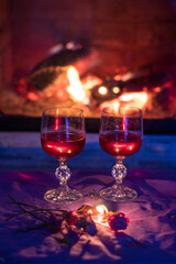 two glasses with red wine, near the fireplace, evening, blurred background