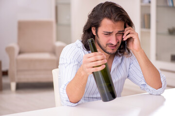 Young man drinking alcohol at home