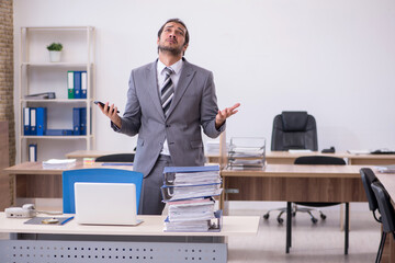 Young male employee unhappy with excessive work in the office