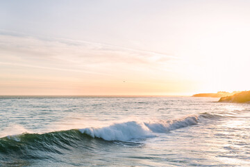 Golden hour sunset with Pacific ocean waves crashing along cliff shoreline of Santa Cruz Bay on California coast - Powered by Adobe