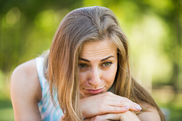 portrait of unhappy european young female sitting on bench in garden
