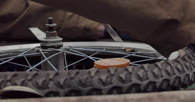 Bicycle repair. The master removes the Bicycle tire from the wheel rim using tablespoons. Closeup.