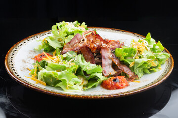 .salad with thin, crispy grilled bacon slices. salad of leaves, pork and cheese