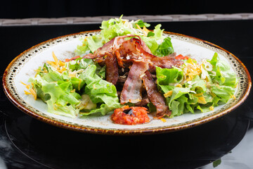 .salad with thin, crispy grilled bacon slices. salad of leaves, pork and cheese