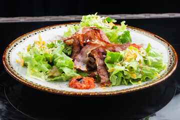 .salad with thin, crispy grilled bacon slices. salad of leaves, pork and cheese