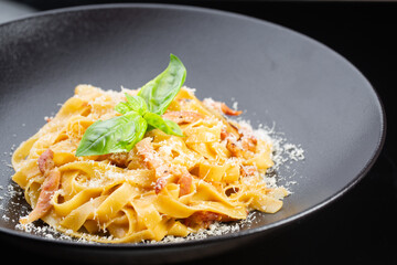 delicious Italian pasta with crispy bacon and cheese, garnished with basil leaves