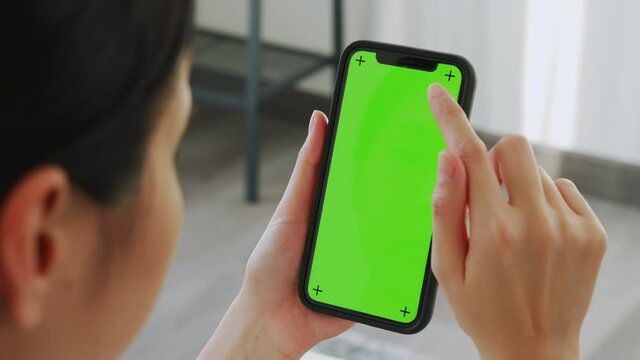 Close up of woman holding in hands a mock up smartphone with green screen for internet online, chromakey screen for advertising.