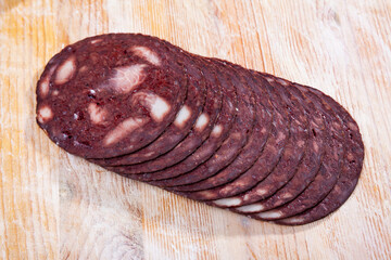 Thin slices of traditional Catalan blood sausage (black botifarra) on wooden background..